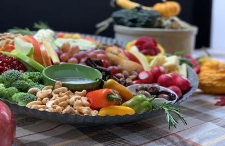 丰收板上摆放着新鲜的蔬菜、坚果、水果和蘸料.